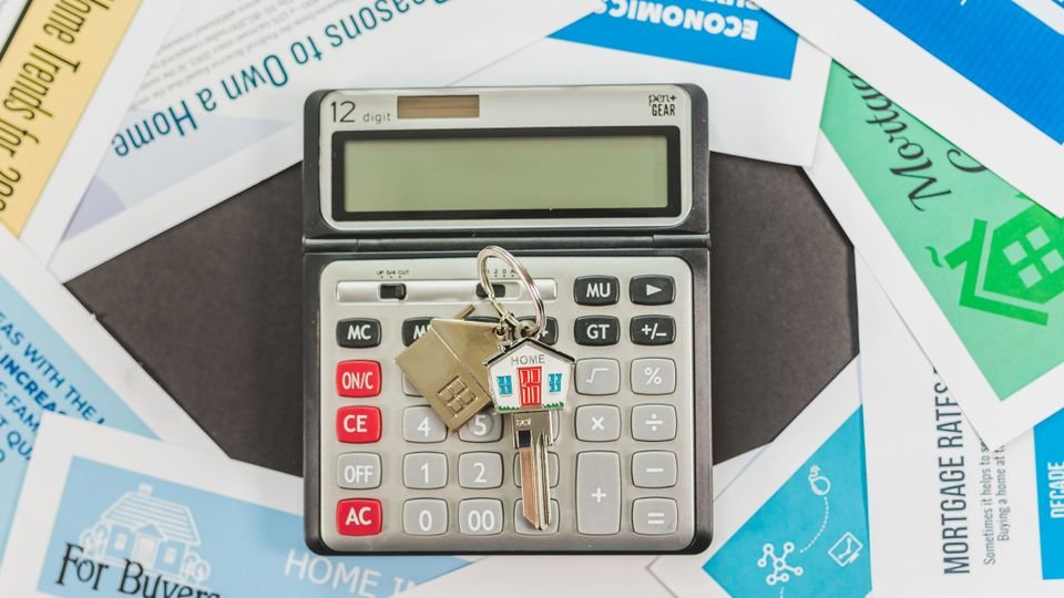 Calculadora, chaves e documentos relacionados a patrimônio e finanças.