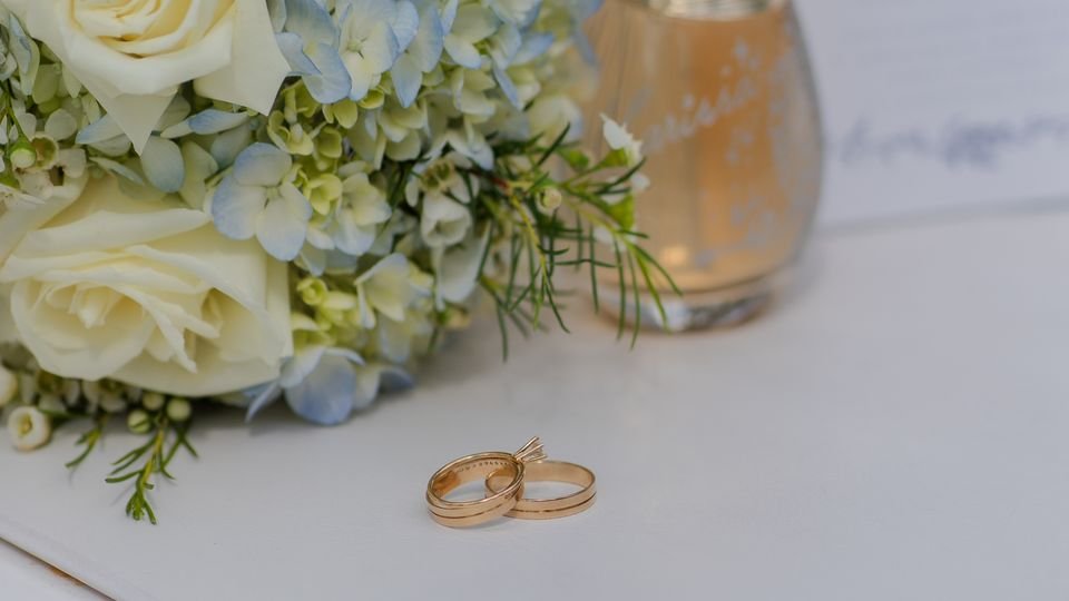 Alianças de casamento sobre uma mesa com arranjo floral.